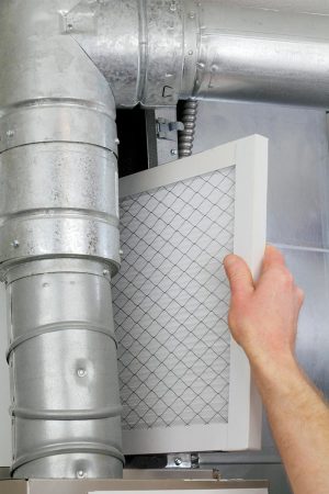 a hand installing a furnace filter