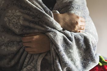 Person wearing a blanket over their shoulders 