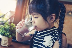 Little girl drinking water from a glass