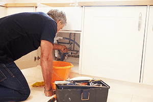 Person doing maintenance under a sink