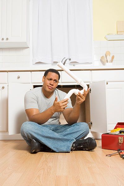 man sitting on the floor holding a broken pipe