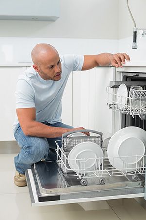 man inspecting his dishwasher 