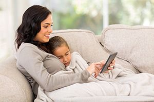 woman and child laying on the couch looking at the phone